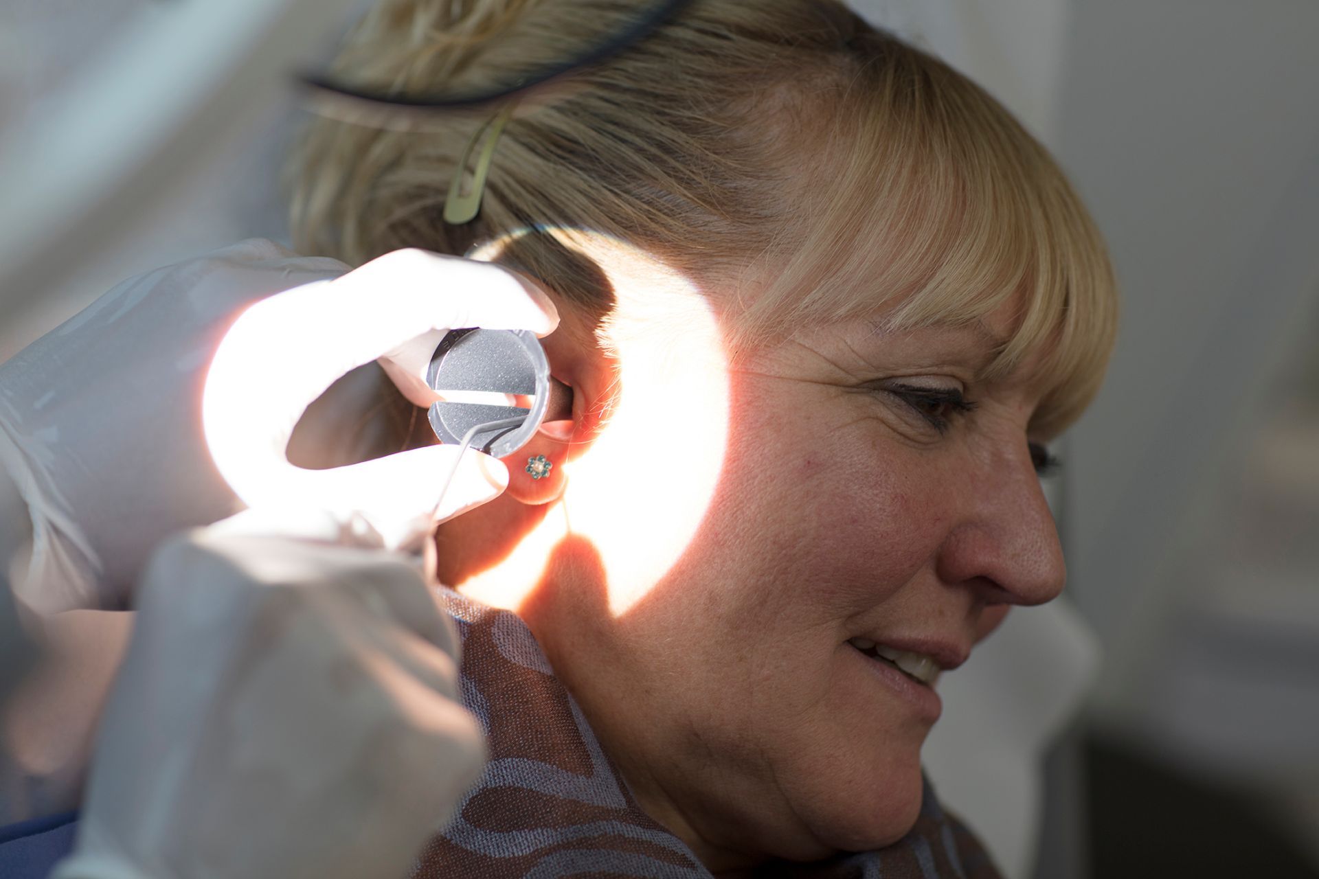 An audiologist using a microsuction handpiece and magnifying loupe to clear ear wax at our Whitchurch, Cardiff clinic